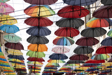 Fototapeta na wymiar A group of different colored umbrella placed next to each other above the street in different colors and shades