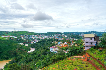 Fototapeta premium Small village in a tea hill valley on a stormy day in the highlands of Da Lat, Vietnam. The place provides a great deal of tea for the whole country