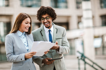 Business people outdoors. Handsome african businessman man and his beautiful female colleague talking to each other outside the office.