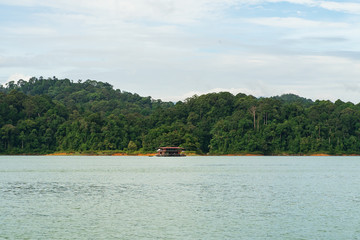 Houseboat cruising through the lake with mountain view at Kenyir Lake. Tasik Kenyir is a man made lake.