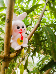 Toy Rabbit of small size in white color and have black eyes sitting in a tree
