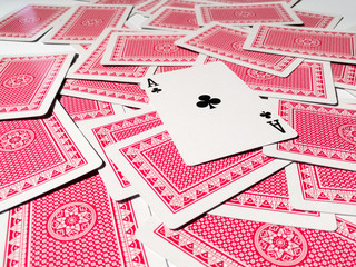 A card with a club suit on a pile of scattered cards from the deck with a red back.