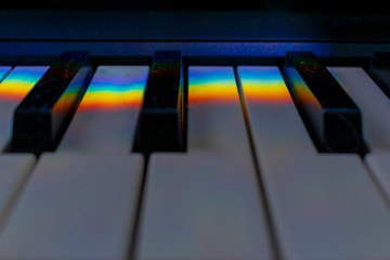 A dusty musical keyboard with rainbow reflections on it