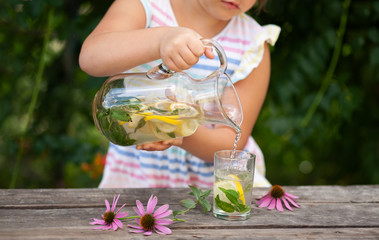 
Girl pours lemonade or mojito from a jug into a glass