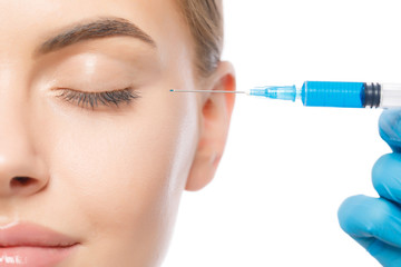 Headshot of young attractive woman pictured with eyes closed during botox injection procedure in...