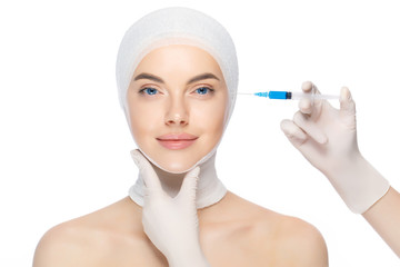 Young beautiful woman with head wrap, prepared for syringe injection into skin by beautician, isolated on white background. Beauty practice concept