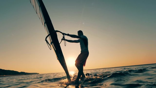 Sailboard is getting navigated through the sunset sea
