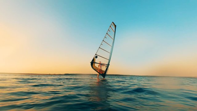 Sailboarder is navigating a windsurf board through the water