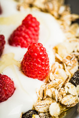 Healthy and tasty breakfast with muesli, yogurt, raspberry and honey. Selective focus. 