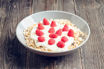 Healthy and tasty breakfast with muesli, yogurt, raspberry and honey. Selective focus. 