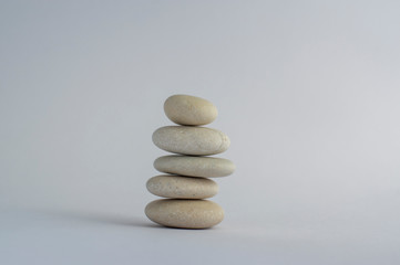 One simplicity stones cairn isolated on white background, group of five white pebbles in tower