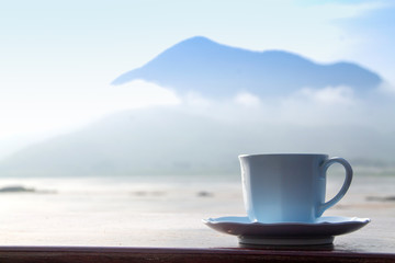 White coffee cup on mountain background in the morning near the river