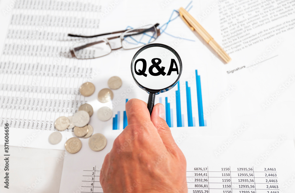 Poster q and a written on white paper on office table with charts diagrams contract and financial documents