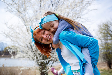 little girl child and mother woman walks through the spring forest with flowering trees, laugh and play, the beginning of spring, family vacation, love of parents