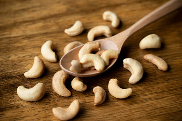 Top view of Tasty cashew nuts on wooden spoon. Selective focus on some cashew.