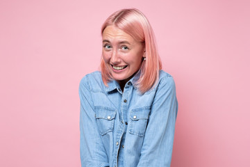 Woman with pink dyed hair smiling looking shy at camera