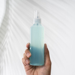 gesture of hand holding plastic bottle hand sanitizer product mockup