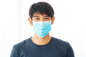 Close up of  Asian man portrait wear blue shirt protection flu cold caronavirus facial mask isolated on white background.