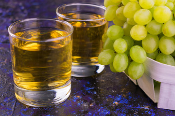 
Two glasses with grape juice and fresh grapes on a blue background.