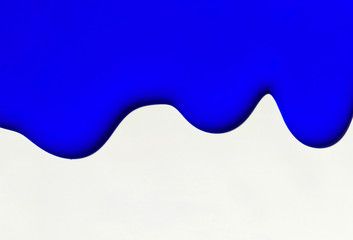 Bright blue paint flows on a white background.Copy space.