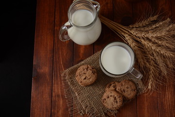 Chocolate chip cookies  with milk on rustic wooden table