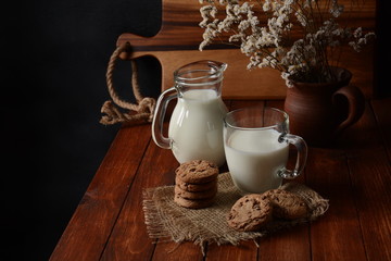 Chocolate chip cookies  with milk on rustic wooden table