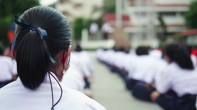 Slow motion of Asian female high school students in white uniform on the semester start wearing mask standing in line during the Coronavirus 2019 (Covid-19) epidemic.