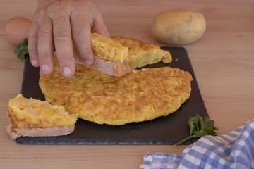 Mano cogiendo un trozo de tortilla de patatas