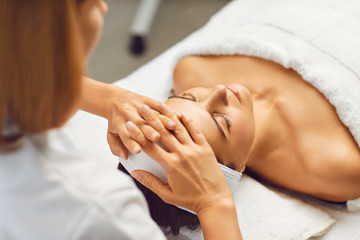 Obraz na płótnie Canvas Facial skin beauty and health concept. A woman receives a facial massage from a clinic beautician