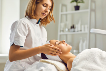 Facial skin care procedures. Beautician makes a massage procedure with a woman's face in a cosmetic...
