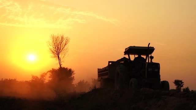 slow motion shot of a tractor working in the fields at sunset in punjab, pakistan