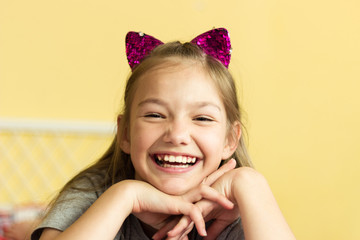 girl laughs on a yellow background on the head pink cat ears