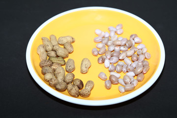 Raw peanuts top view isolated on yellow plate at black background