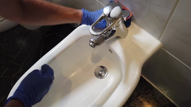 Hand mit Gummihandschuhen reinigt Bad Waschbecken Toilette WC