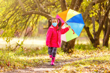 Little girl wearing medical face mask prevent pollution on fallen leaves at park.