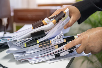 Office workers arranging stacks of lot paperwork files for searching infomation unfinished...