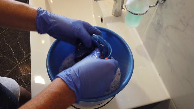 Hand mit Gummihandschuhen reinigt Bad Waschbecken Toilette WC