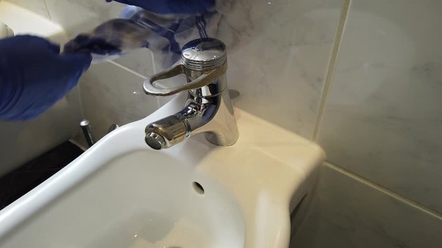 Hand mit Gummihandschuhen reinigt Bad Waschbecken Toilette WC