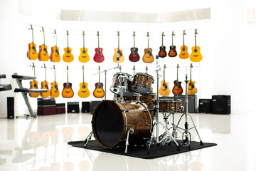 Brown drum set with blurry many guitar on white background in music show room of music shop.