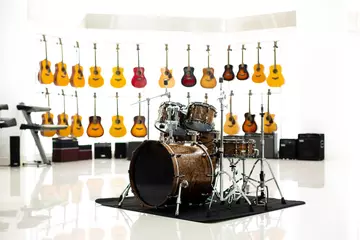 Wall murals Music store Brown drum set with blurry many guitar on white background in music show room of music shop.