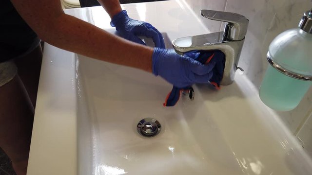 Hand mit Gummihandschuhen reinigt Bad Waschbecken Toilette WC