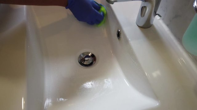 Hand mit Gummihandschuhen reinigt Bad Waschbecken Toilette WC