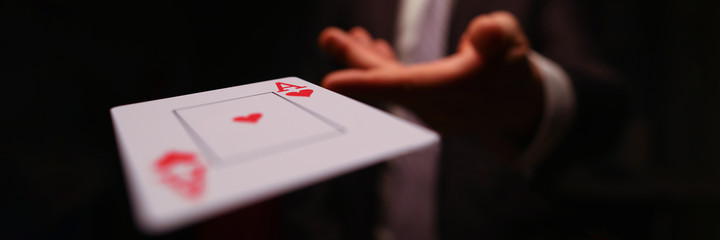 Close-up of male hand throwing trump card. Professional player or magician in presentable suit....