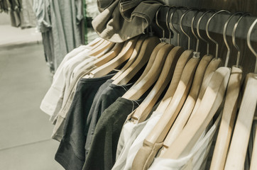 White and gray tone  fabric shirts hanging on a rack in a store.