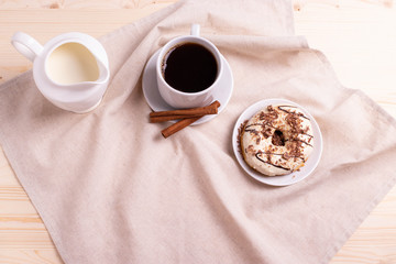 black coffee in a ceramic cup and a doughnut on rustic style table
