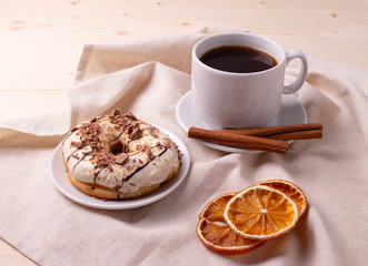 black coffee in a ceramic cup and a doughnut on rustic style table
