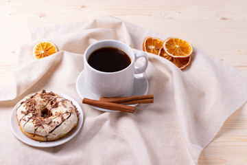 black coffee in a ceramic cup and a doughnut on rustic style table
