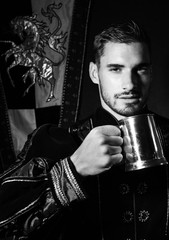 Portrait of handsome king with beard dressed in costume with tankard looking at camera