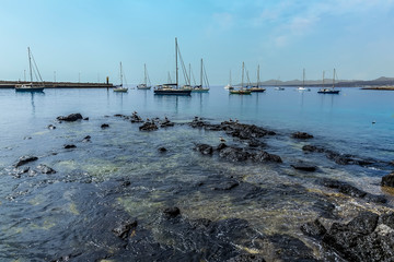 Rocks, gulls and yachts in a sheltered bay in Arrecife, Lanzarote on a sunny afternoon