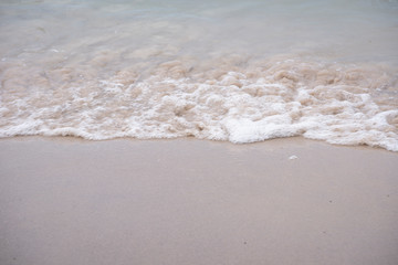 Soft ocean wave on tropical sandy beach in rainy season